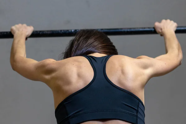 The girl is engaged on the bar in the gym