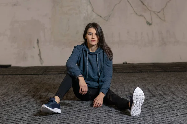 Kız spor salonunda yerde oturuyor