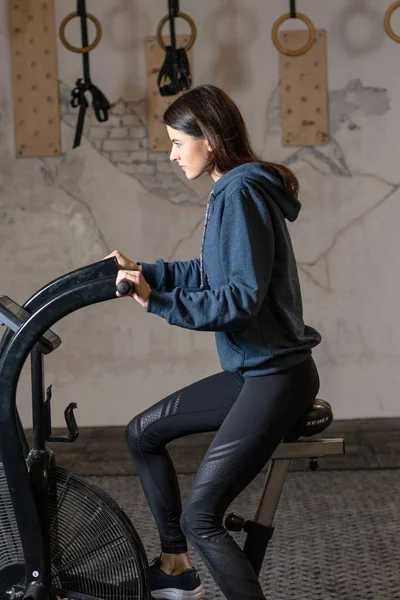 这个女孩在健身房里骑着一辆交叉健身的健身自行车。 — 图库照片