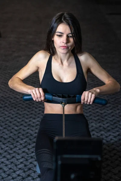 Flickan är engagerad i en rodd Simulator i gymmet — Stockfoto
