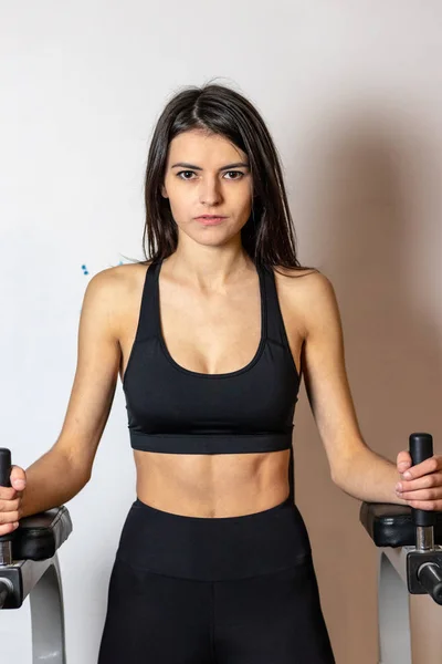 A menina faz exercício na imprensa sobre o simulador no ginásio — Fotografia de Stock