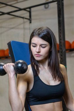 Kız spor salonunda dambıllarla meşgul.