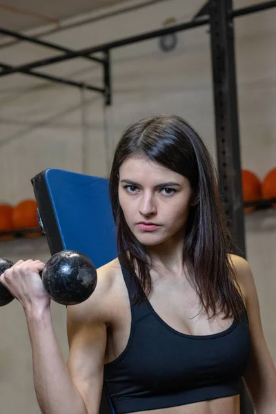 Het meisje is verloofd met halters in de sportschool. — Stockfoto