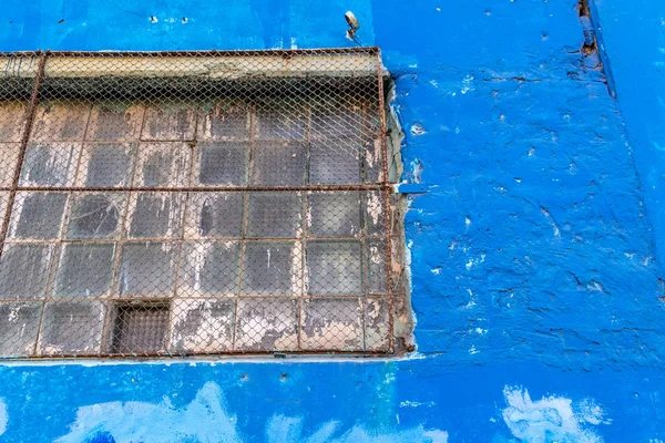 Venster met een rooster op een blauwe muur — Stockfoto