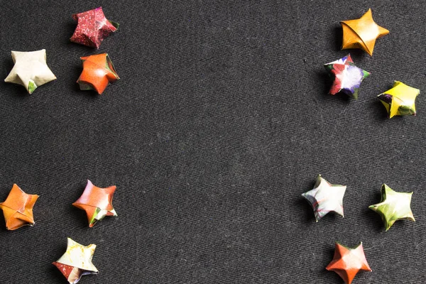 Estrellas de papel de diferentes colores sobre un fondo negro — Foto de Stock