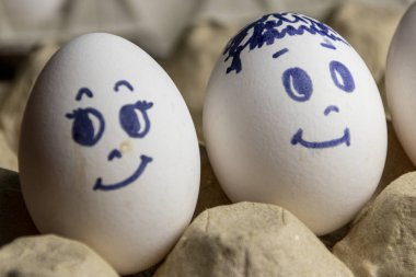 Karton kutuda güzel yumurtalar. Duyguları olan yumurtalar. Farklı yüzler üzerine boyanmış karton kutuda beyaz yumurtalar. Erkek ve kız
