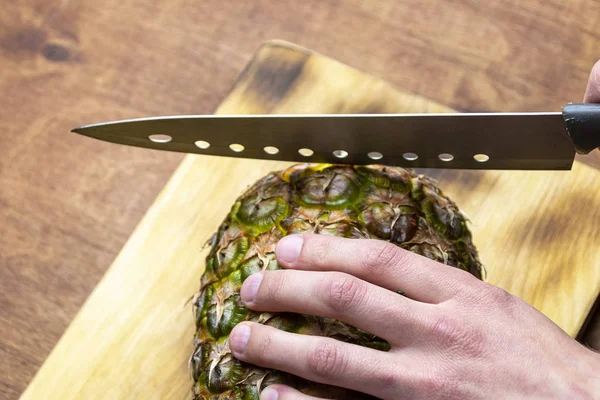 Kız ferahlatıcı bir Smoothie yapmak için ahşap bir arka planda ananas keser