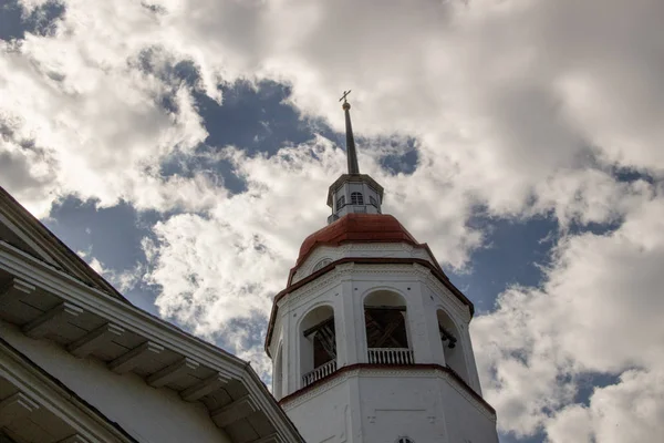 Gammal sten och vit målar kyrka med klockstapel och bjällror mot blå himmel — Stockfoto