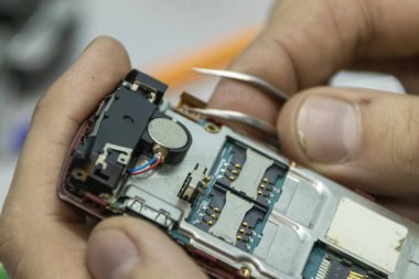 Yaşlı ve genç erkekler birlikte bir cep telefonu tamir. Bir tamirciye çalışır. Onlar farklı araçlar kullanabilir. Onlar tamir uzmanlar vardır