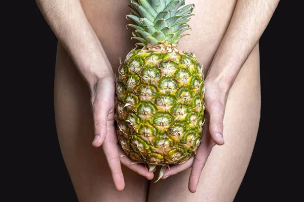 Beautiful young girl covers pineapple intimate places on a black background, sugaring for skin