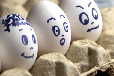 Karton kutuda güzel yumurtalar. Duyguları olan yumurtalar. Farklı yüzler üzerine boyanmış karton kutuda beyaz yumurtalar. Erkek ve kız