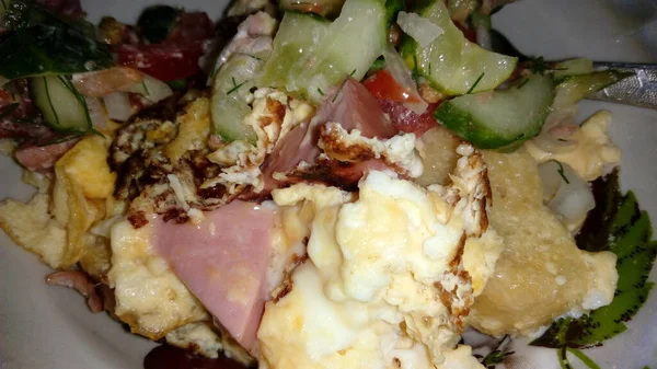 Heerlijke gebakken eieren met groenten en vlees op een bord — Stockfoto