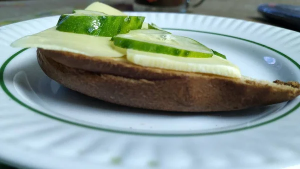 Бутерброд с сыром и огурцом, на столе в тарелке — стоковое фото