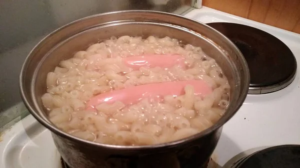 Macaroni est cuit dans une casserole avec des saucisses — Photo
