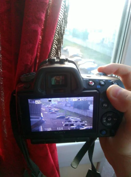 Fotograf trzyma lustrzankę i fotografuje uliczne ognisko na monitorze kamery — Zdjęcie stockowe