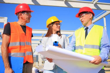 Kadın mimar, inşaat mühendisi ve inşaat alanındaki projeden bahseden müdür. Takım çalışması ve insanlar konsepti - mimar ve inşaatçılar grubu, olumlu duygular, neşe ve gülümseme