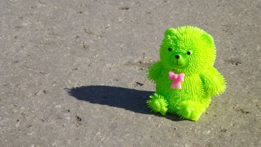 Yeşil oyuncak ayı asfalt yolda.