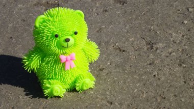 Yeşil oyuncak ayı asfalt yolda.