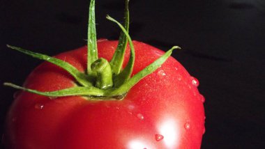 Siyah zemin üzerine kırmızı olgun domates.