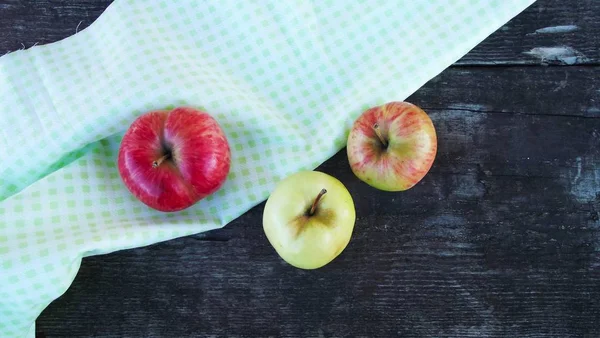 Fresh sweet apples on light napkin on wooden background.