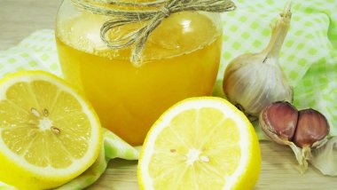 Doğal şifa, alternatif tıp. Dokunulmazlık güçlendirilmesi için sağlıklı malzemelerle. Tatlım, sarımsak ve limon ahşap rustik masa üzerinde.