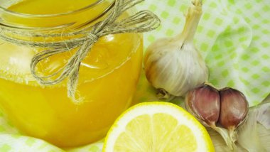 Doğal şifa, alternatif tıp. Dokunulmazlık güçlendirilmesi için sağlıklı malzemelerle. Tatlım, sarımsak ve limon ahşap rustik masa üzerinde.