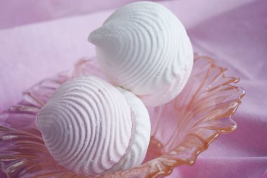 Vanilya ve meyve şekerlemeleri bir vazoda pembe peçete üzerinde.