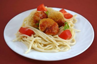 Köfte domates ve beyaz bir plaka üzerinde otlar ile lezzetli makarna.