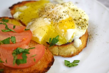 Çıtır çıtır kızarmış ekmek, sahanda yumurta ve domates kahvaltıda beyaz bir plaka üzerinde.