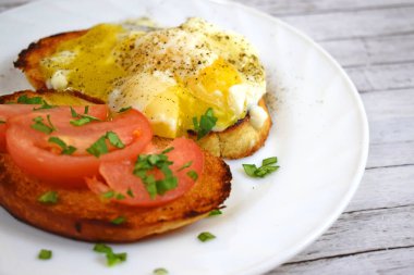 Çıtır çıtır kızarmış ekmek, sahanda yumurta ve domates kahvaltıda beyaz bir plaka üzerinde.