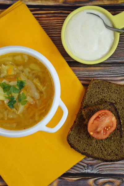 Delicious homemade soup from fresh cabbage on a wooden background.