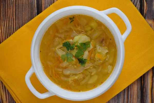 Delicious homemade soup from fresh cabbage on a wooden background.