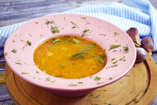 Delicious hot soup with rice, garlic and hot pepper on wooden background.