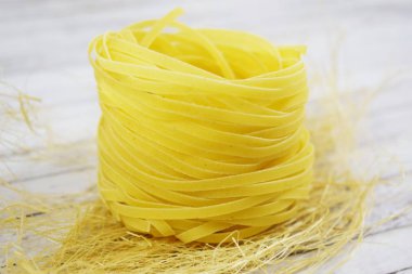 Ahşap arka plan üzerinde bir yuva şeklinde makarna.