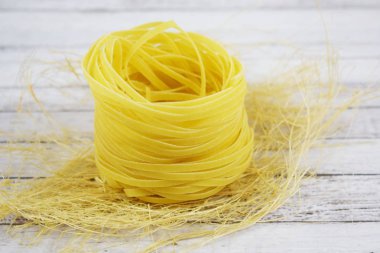 Ahşap arka plan üzerinde bir yuva şeklinde makarna.