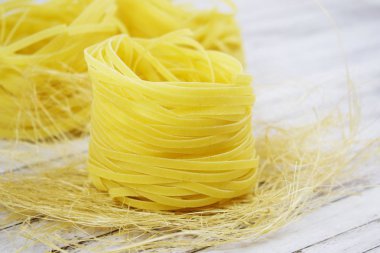 Ahşap arka plan üzerinde bir yuva şeklinde makarna.