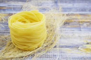 Ahşap arka plan üzerinde bir yuva şeklinde makarna.