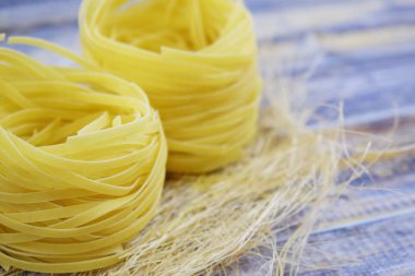 Ahşap arka plan üzerinde bir yuva şeklinde makarna.