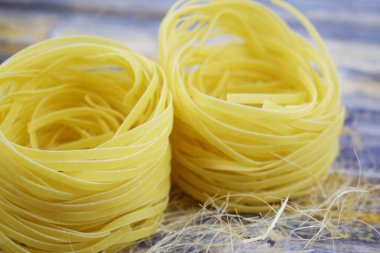 Ahşap arka plan üzerinde bir yuva şeklinde makarna.