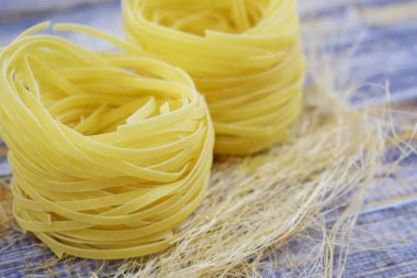 Ahşap arka plan üzerinde bir yuva şeklinde makarna.