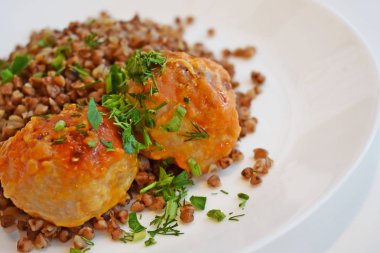 Köfte ve beyaz bir plaka üzerinde otlar ile leziz buğday.