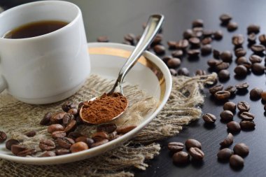 Bir çuval bezi üzerinde beyaz bir fincan hoş kokulu kahve.