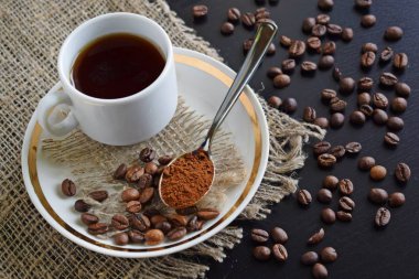 Bir çuval bezi üzerinde beyaz bir fincan hoş kokulu kahve.