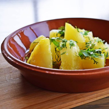 Lezzetli patates tereyağı ve otlar ahşap arka plan üzerinde bir kil çanağı ile.