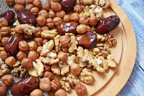 Lezzetli ve sağlıklı fındık ve çuval bezi, ahşap arka plan üzerinde tarihleri.