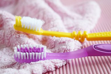Pembe arka planda sarı ve mor diş fırçası.