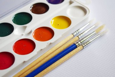 Suluboya boya ve masanın üzerine çizmek için fırçalar.