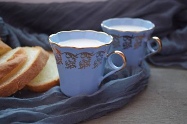 Mavi peçetenin üzerinde mavi fincan ve dilimlenmiş ekmek ile süt.