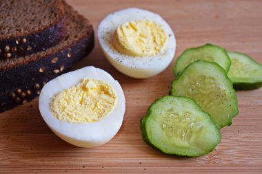 Ahşap arka plan üzerinde siyah ekmek ve taze salatalık ile Haşlanmış yumurta.