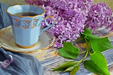 Mavi bir fincan çay ve taze mor leylak çiçekleri.